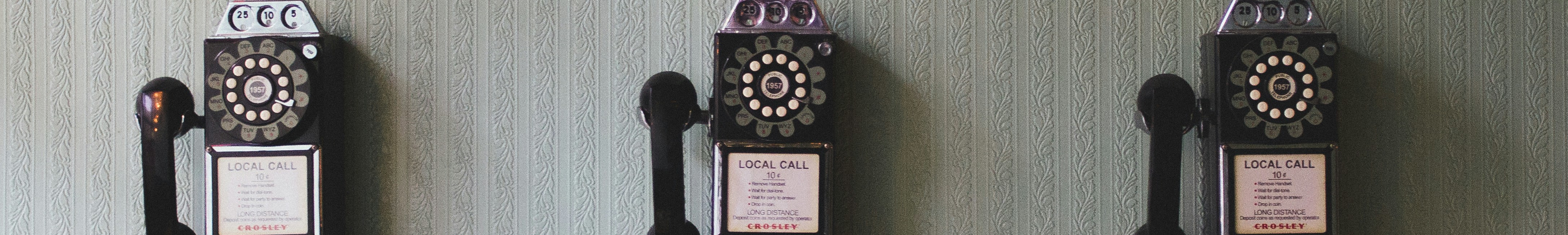 Three old pay phones on a wall - Photo by Pavan Trikutam