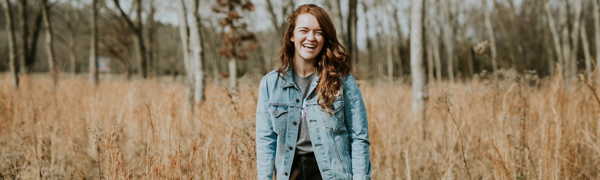 A laughing girl standing in the woods - Photo credit: Brooke Cagle